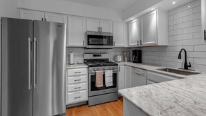 A modern kitchen with stainless steel appliances, white cabinetry, and a granite countertop. - Living Large Downtown (Buffalo)