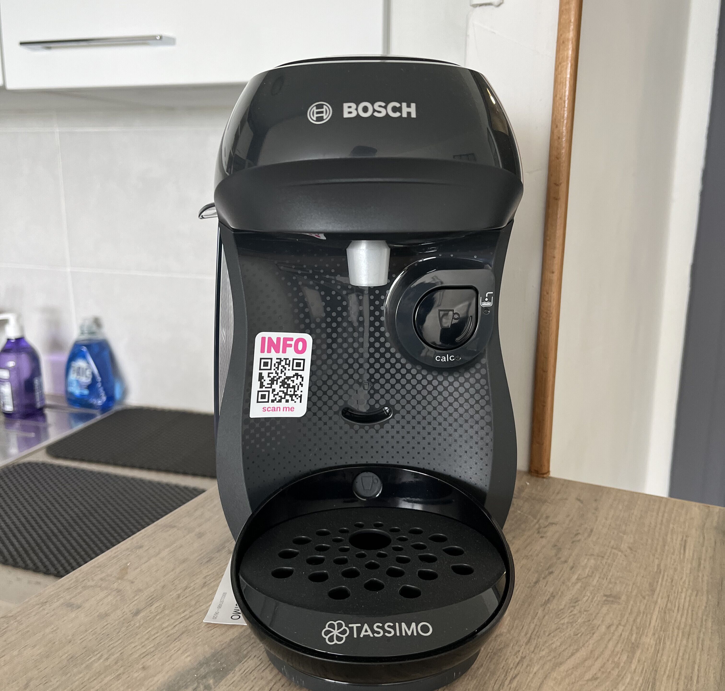 Une machine à café Bosch avec un support pour dosettes Tassimo, posée sur un plan de travail de cuisine.