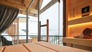 Una cabaña de madera con un ventanal grande, una mesa de madera y una estantería con una toalla enrollada.