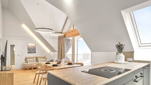 Una cocina moderna con una isla grande, suelo de madera y una zona de comedor con sofá y sillas.