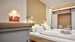 Et moderne soveværelse med sengegavl i træ, et natbord med lampe og en indbygget garderobe med hylder.