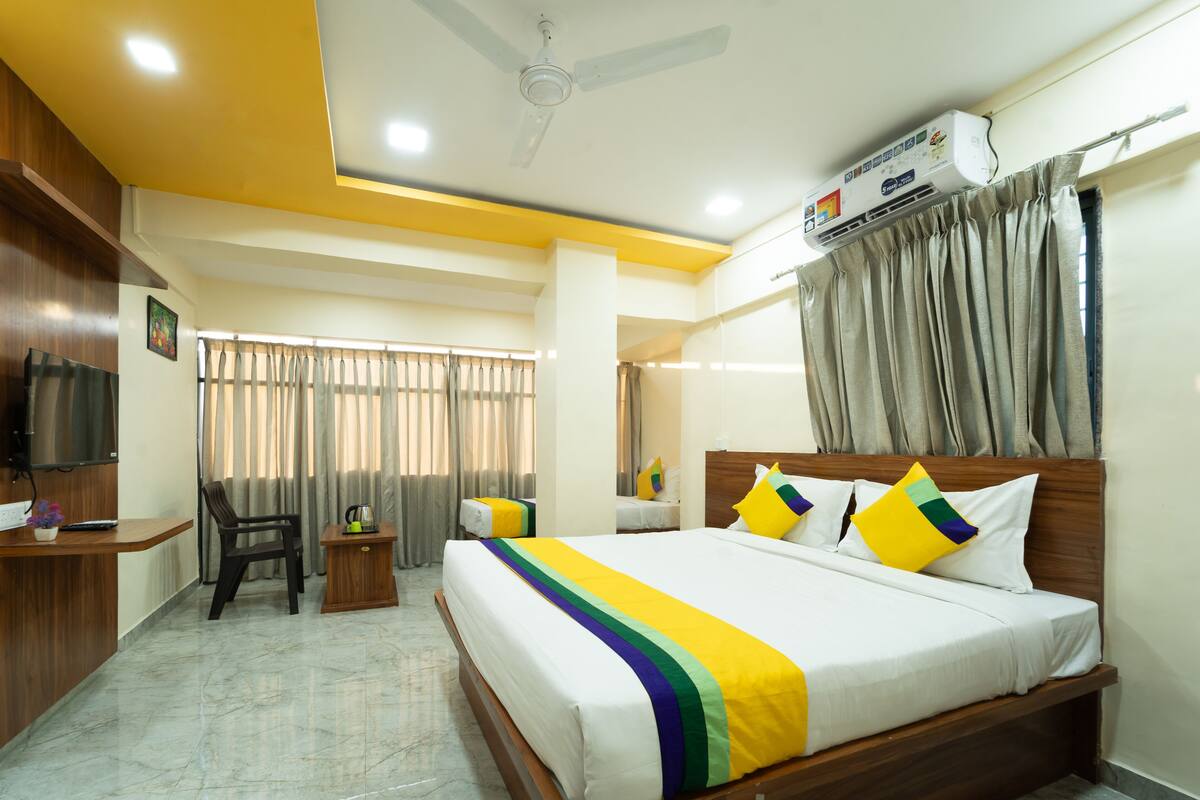 A hotel room with a bed, a desk, a chair, a TV, and a ceiling fan.
