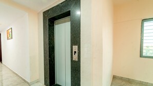 Un pasillo con piso de mármol, una puerta enmarcada en mármol y un interruptor de luz en la pared.