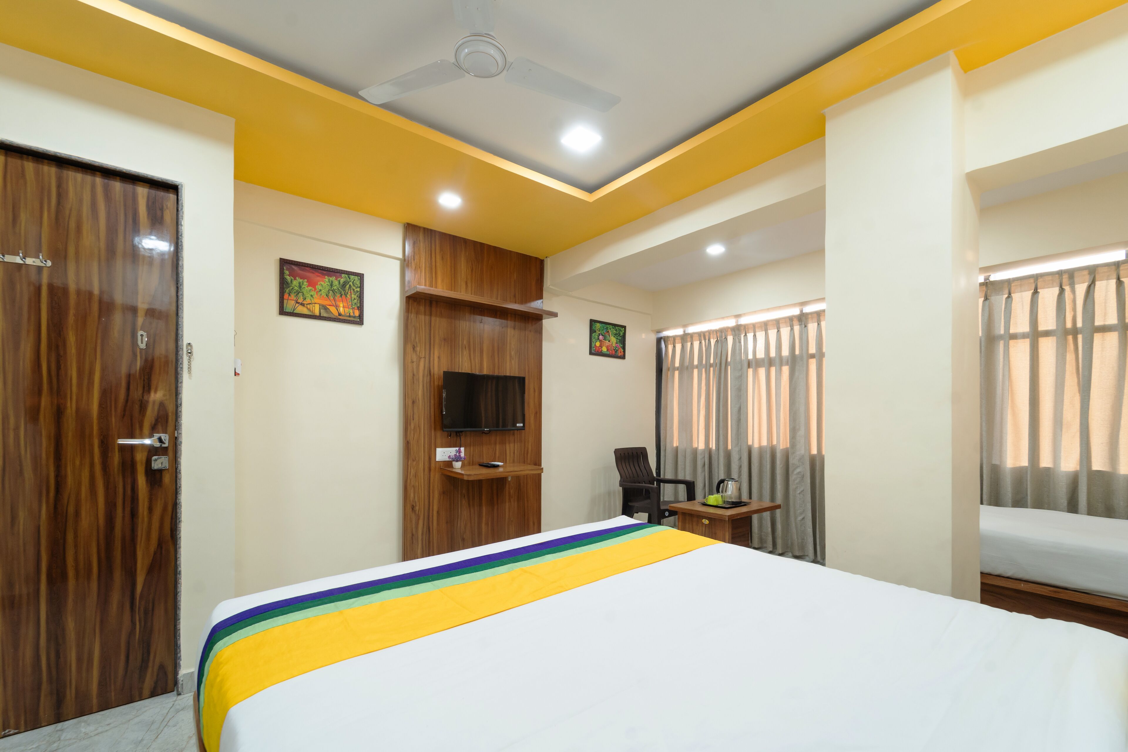 A hotel room with a bed, a desk, a chair, a television, and curtains.