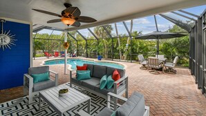 An outdoor patio with a pool, seating area, and a ceiling fan. - Gorgeous Beach Home with heated pool and close to beach!  Pet friendly (Holmes Beach)