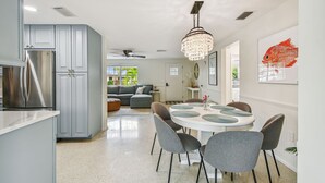 A modern kitchen with grey cabinets, a stainless steel refrigerator, and a chandelier. - Gorgeous Beach Home with heated pool and close to beach!  Pet friendly (Holmes Beach)