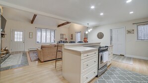 A spacious kitchen with a large island, a dining area with a sofa, and a living room with a fireplace. - Peaceful Cavendish Retreat w/ Hot Tub & Fireplace! (Proctorsville)