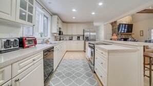 A modern kitchen with white cabinetry, a built-in oven, a microwave, and a coffee maker. - Peaceful Cavendish Retreat w/ Hot Tub & Fireplace! (Proctorsville)