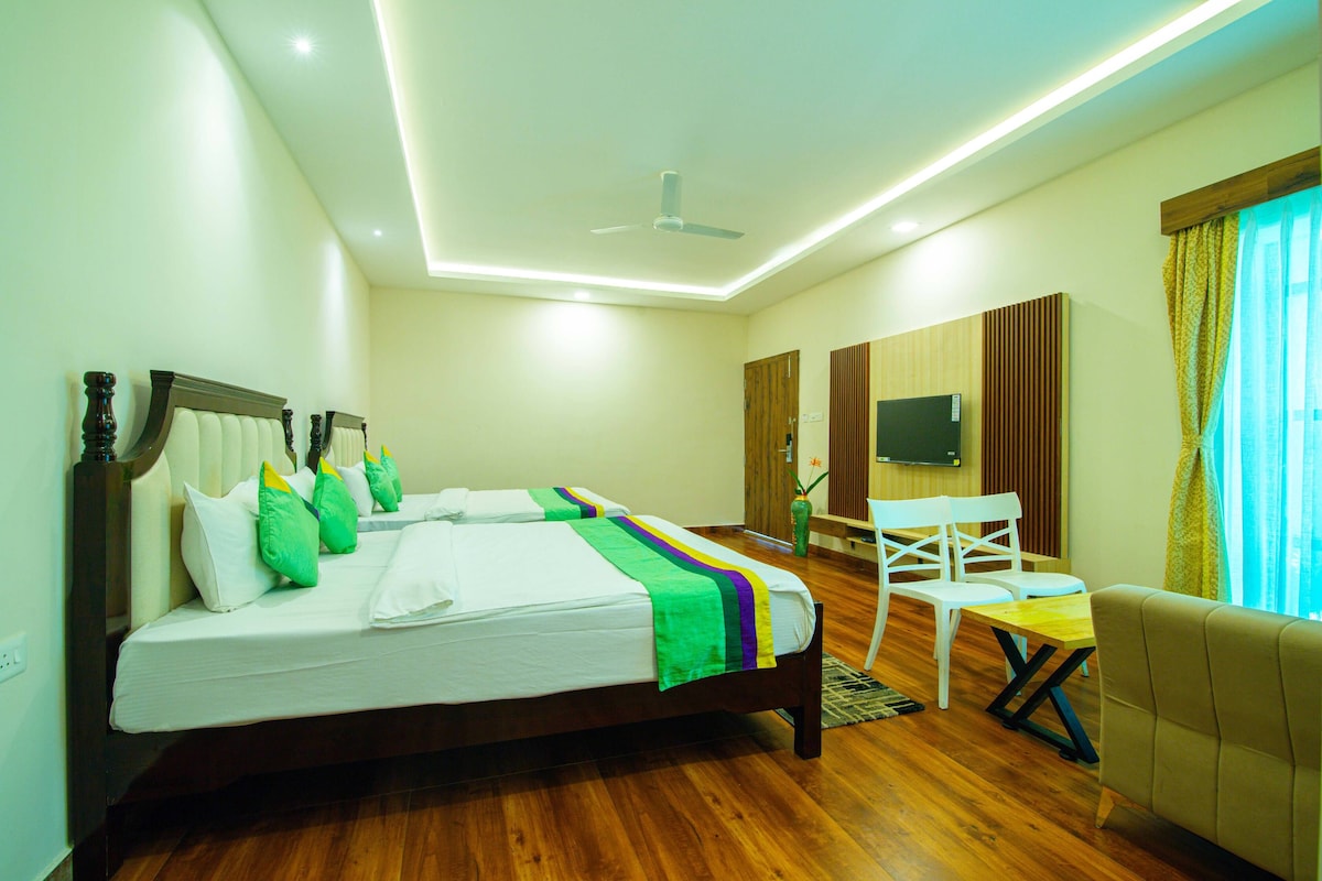 A hotel room with a large bed, a TV, a desk, and a chair.