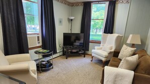 A living room with a TV, two armchairs, a sofa, a coffee table, and a lamp.