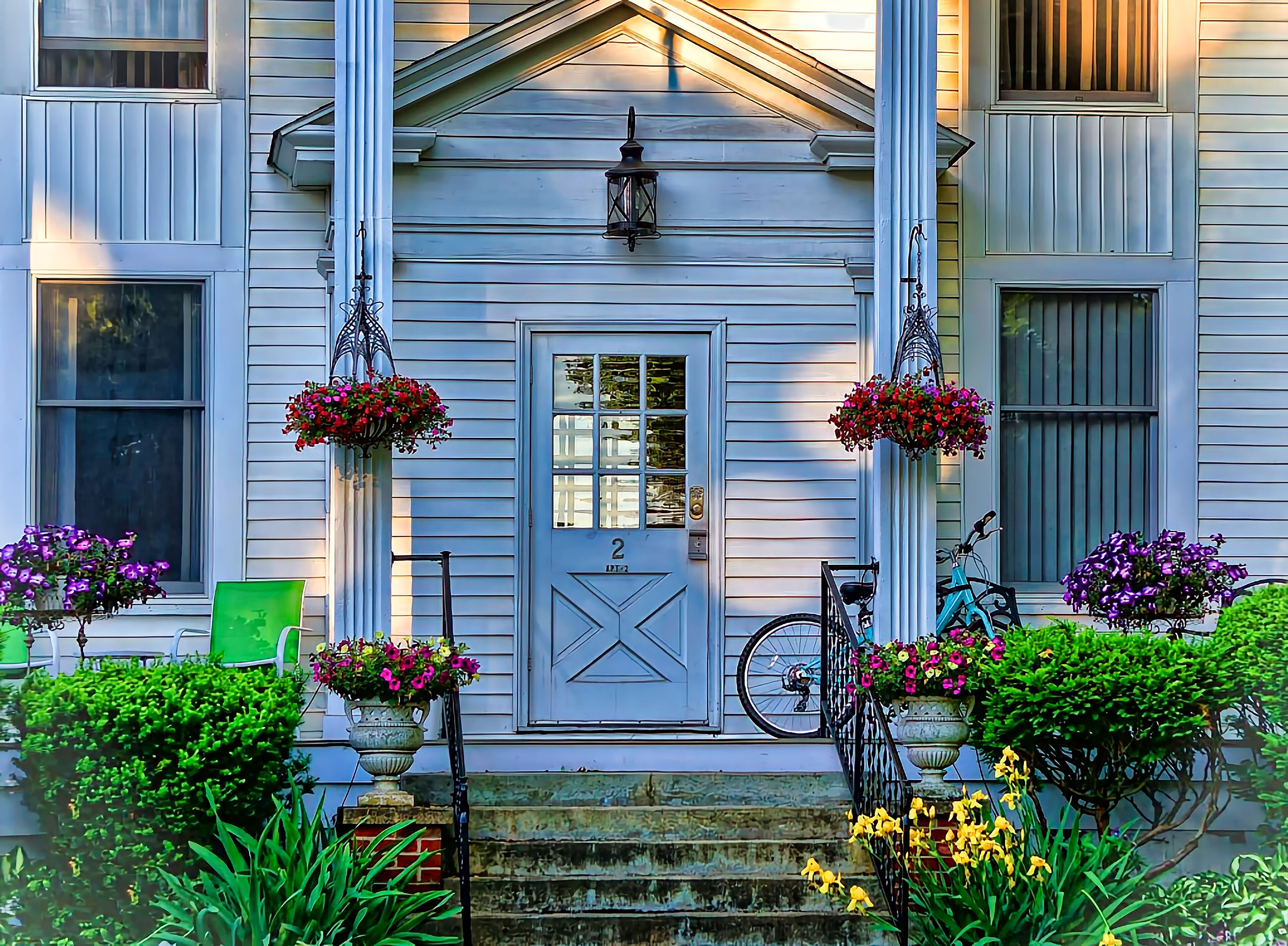 A house with a front porch, a door with a number, and hanging flower baskets.