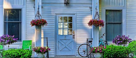A house with a front porch, a door with a number, and hanging flower baskets.