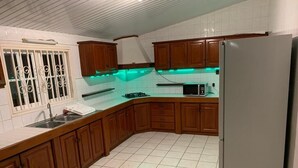 Una cocina con armarios de madera, un refrigerador de acero inoxidable, un microondas y una estufa a gas.