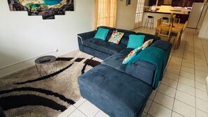 Una sala de estar con un sofá, una alfombra y un cuadro colgado en la pared.