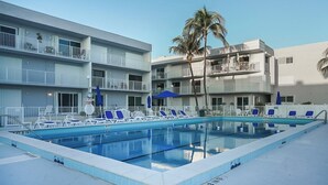 A swimming pool with lounge chairs, a no diving sign, and a building with balconies.