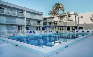 A swimming pool with lounge chairs, a no diving sign, and a building with balconies.