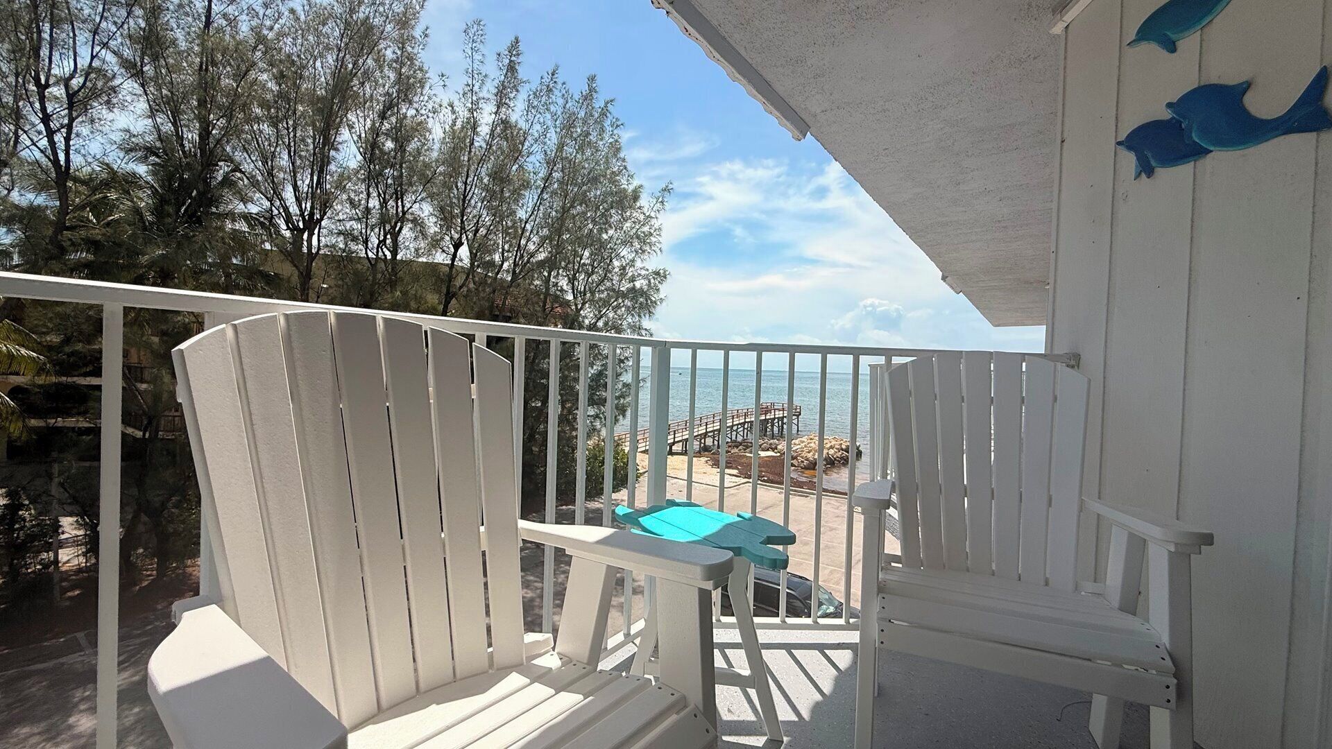A white balcony with a view of the sea and a wooden deck.