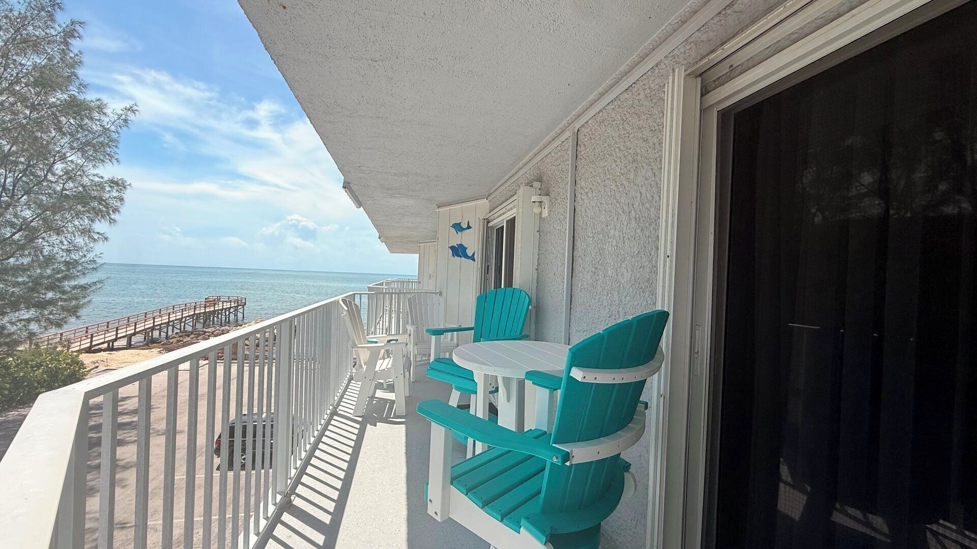 A balcony with a table and chairs, a view of the ocean, and a wooden deck.