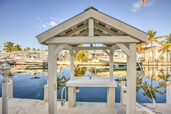 A gazebo with a pool, surrounded by boats and palm trees.