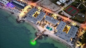 An aerial view of a coastal hotel with a pool, tennis courts, and a pier extending into the water. - Salty Breezes Condo 2bed 2bath second floor with elevator, pool & ocean front! (Key Colony Beach)