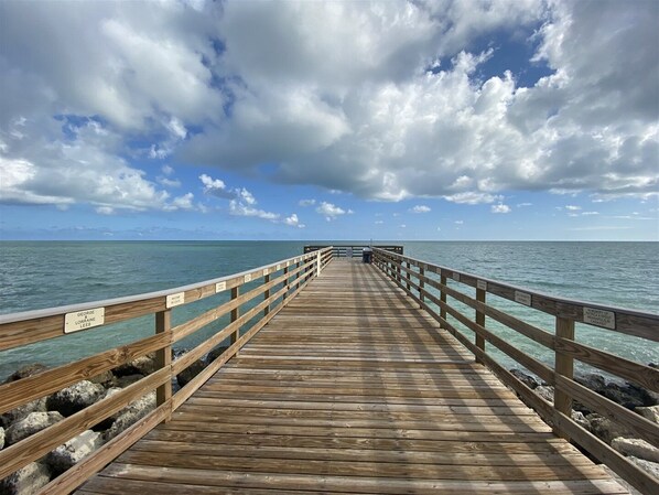 A wooden pier extending into the ocean with a clear sky above.