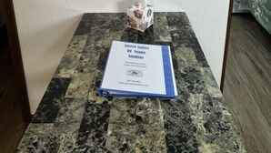 A room with a marble table, a framed painting of flowers, a tissue box, and a booklet titled "Sweet Sulties of Nome Studios". - Clean and Quiet Studio Apartment C (Nome)