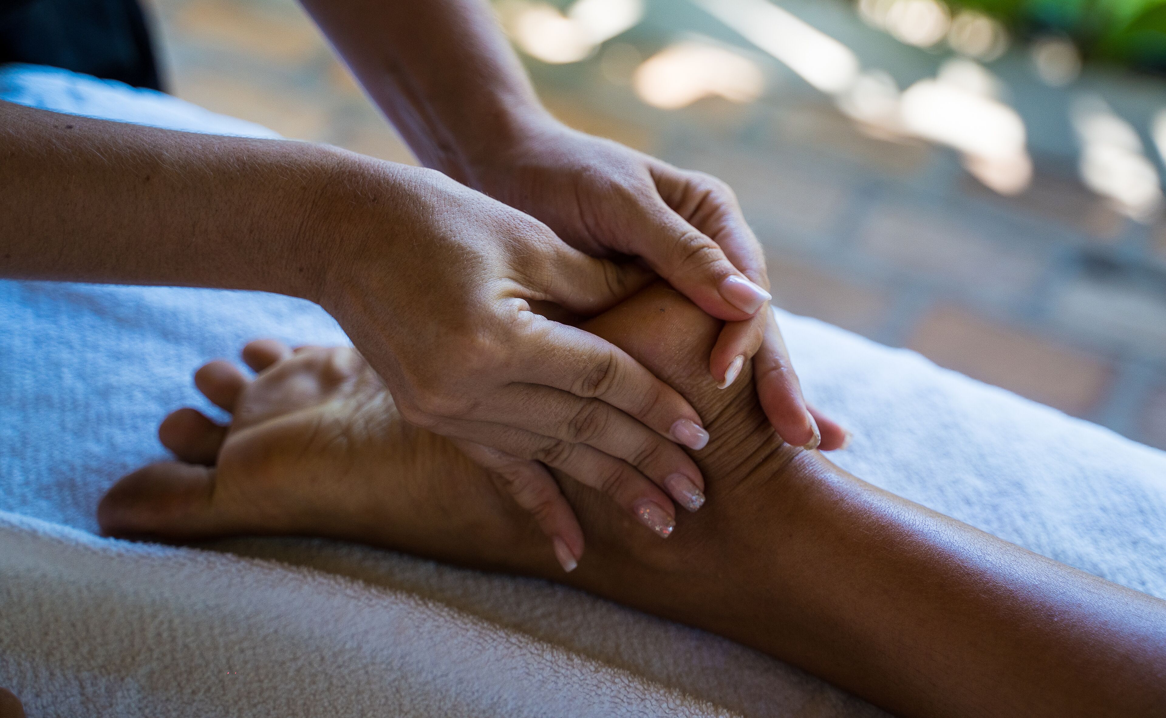 A close-up of hands performing a foot massage on a foot.