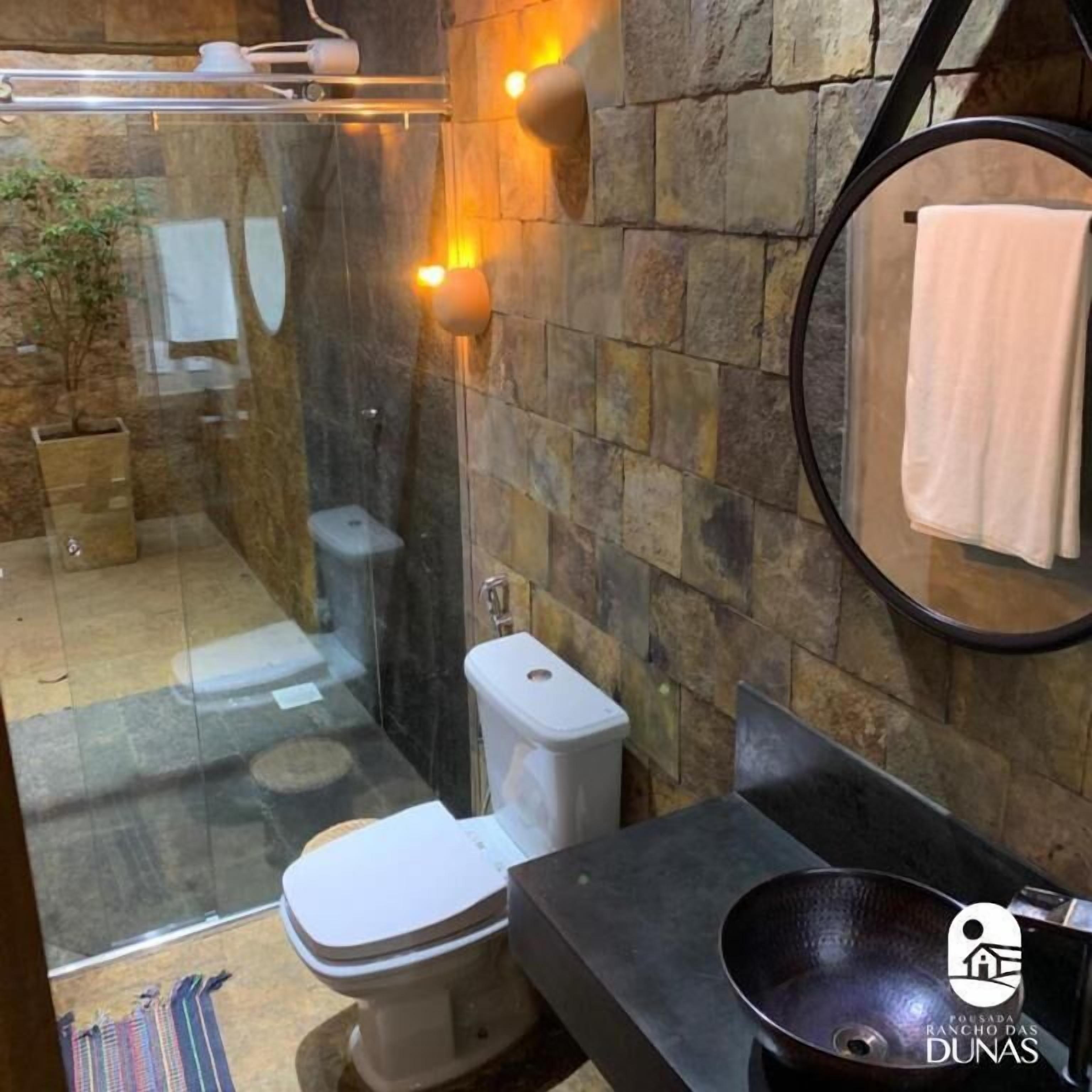 Een moderne badkamer met een douchecabine van glas, een toilet en een wastafel met een zwarte wasbak.