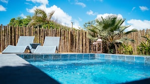 A swimming pool with two lounge chairs and a bamboo fence in the background. - Hotel Pousada Rancho das Dunas (Santo Amaro do Maranhão)