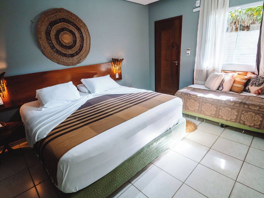 A hotel room with a large bed, a smaller bed, a wall-mounted circular decorative item, and a nightstand with a phone and a lamp.