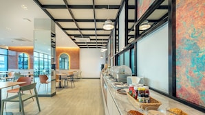 A modern dining area with a buffet setup, including various food containers and condiments. - PLAAI Plus Hotel Bowin (Pluak Daeng)