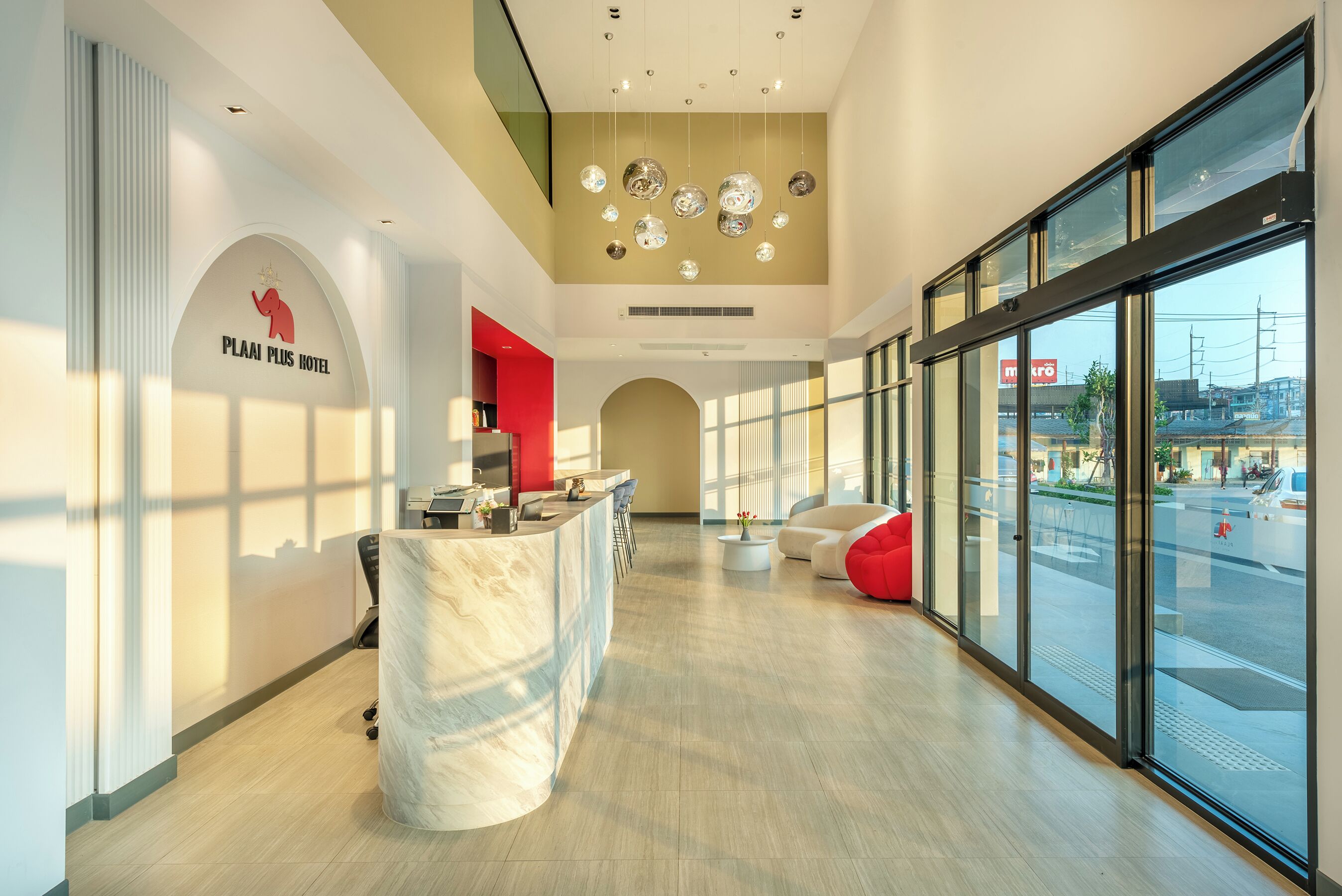 Un moderno vestíbulo de hotel con mostrador de recepción, zona de estar y amplios ventanales con vistas a la calle.