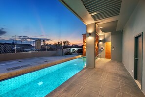 Una piscina interior moderna con agua azul cristalina, rodeada por una solana con baldosas y un paseo cubierto.