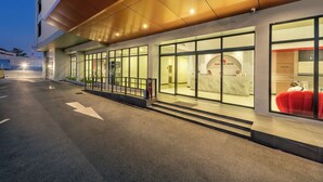 A modern hotel entrance with glass doors, a reception desk, and a staircase leading to the lobby. - PLAAI Plus Hotel Bowin (Pluak Daeng)