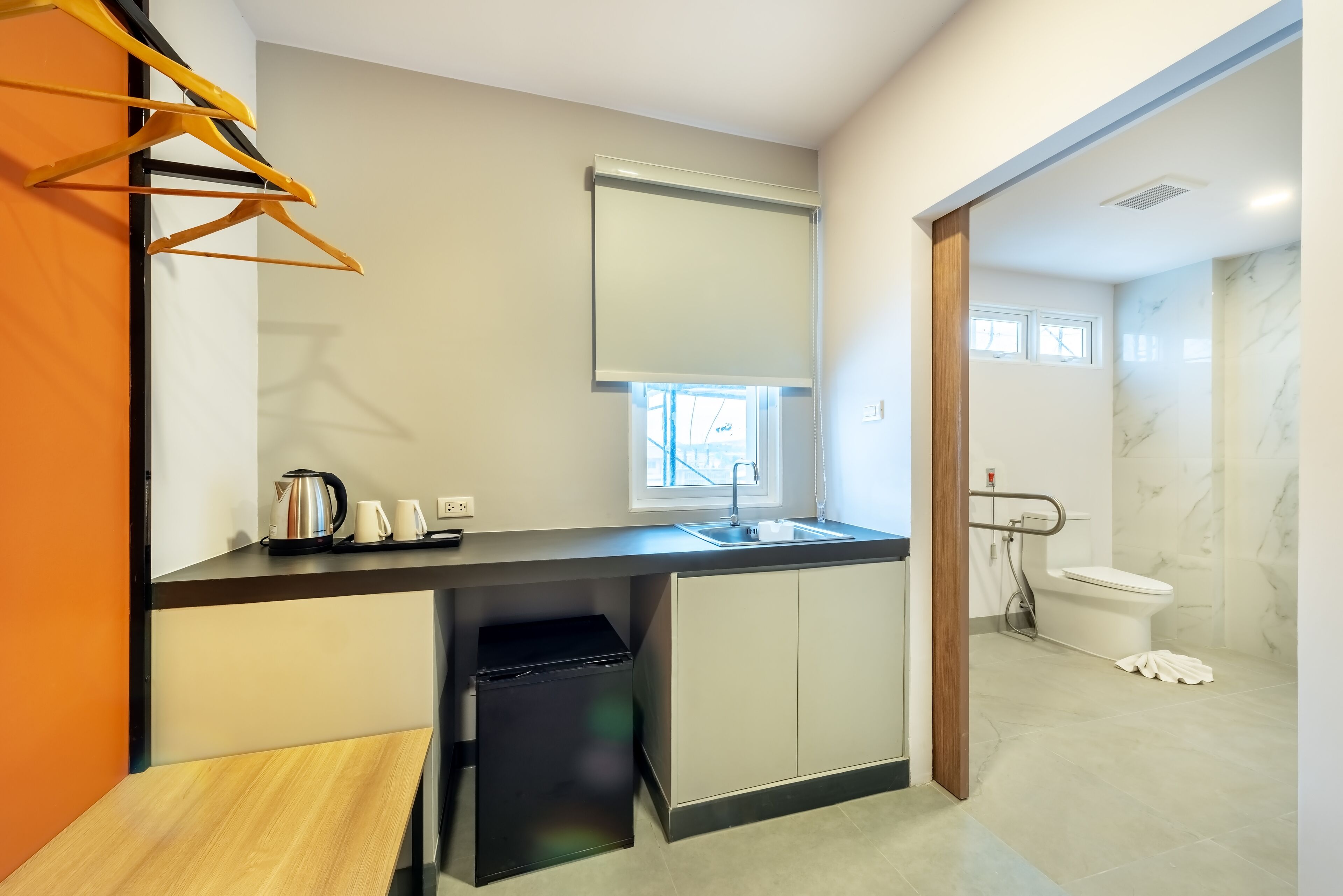 A compact kitchen with a sink, a window, and a small trash bin.