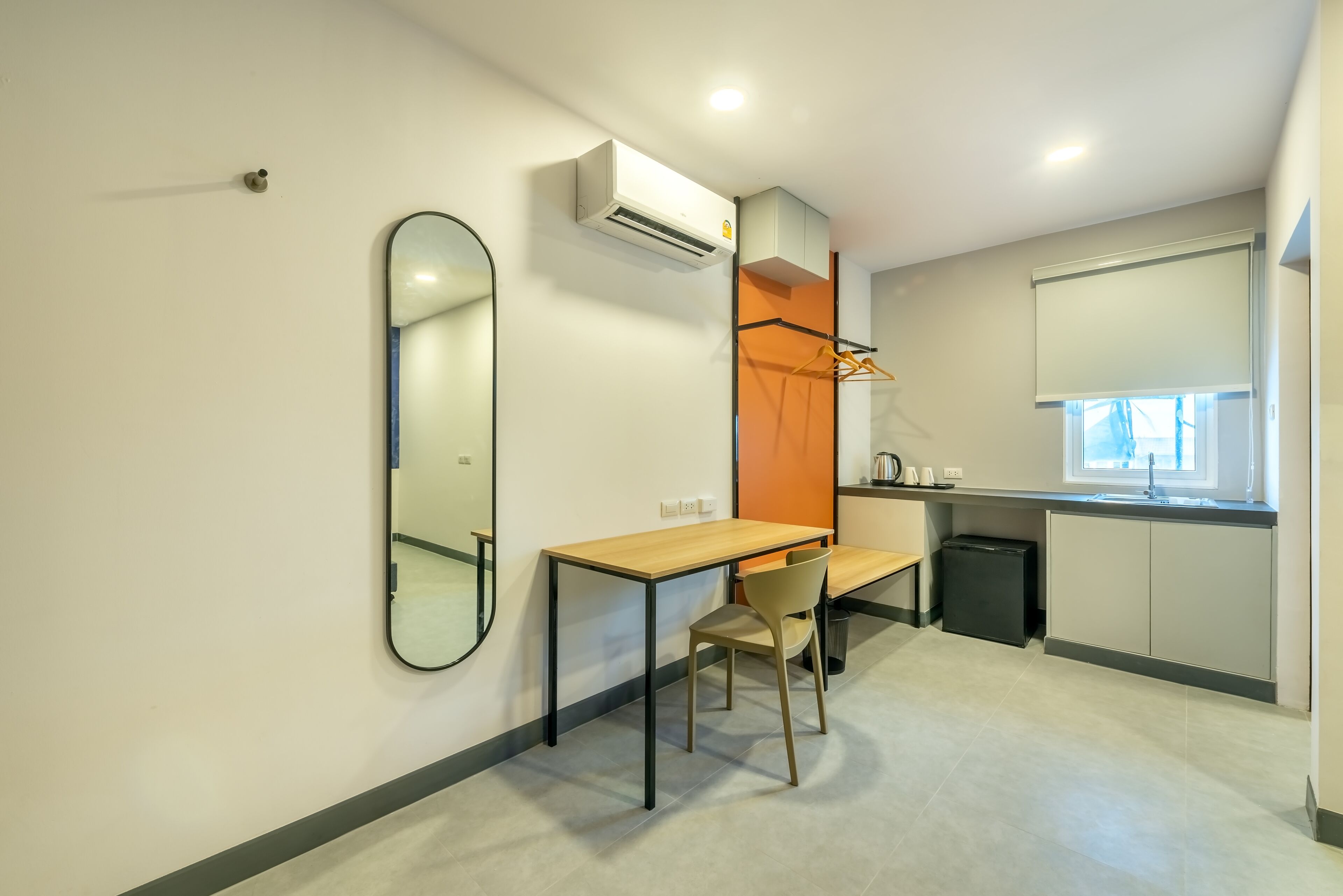 A compact kitchenette with a wooden table, a chair, and a mirror.