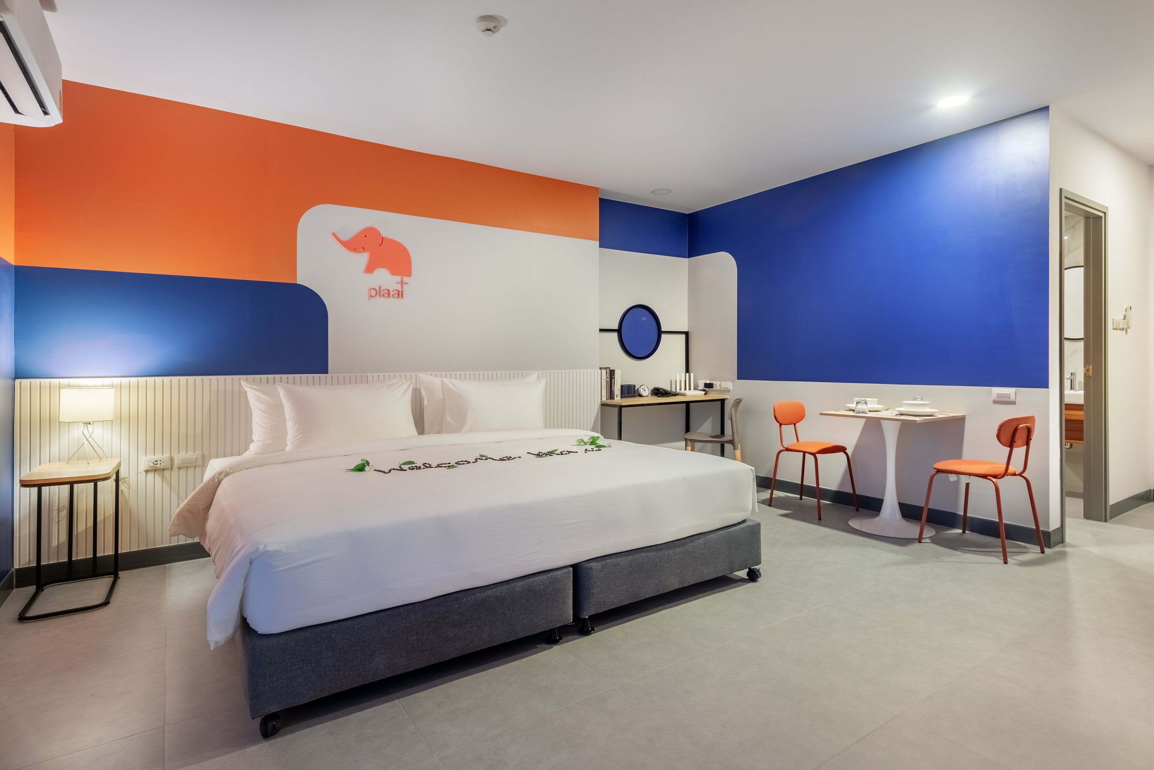 A modern hotel room with a large bed, a desk, and two chairs.
