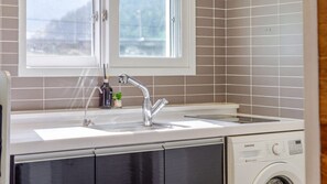 A modern kitchen with a stainless steel sink, a built-in dishwasher, and a window above the sink. - Geoje Beachwhite Pension (Geoje)
