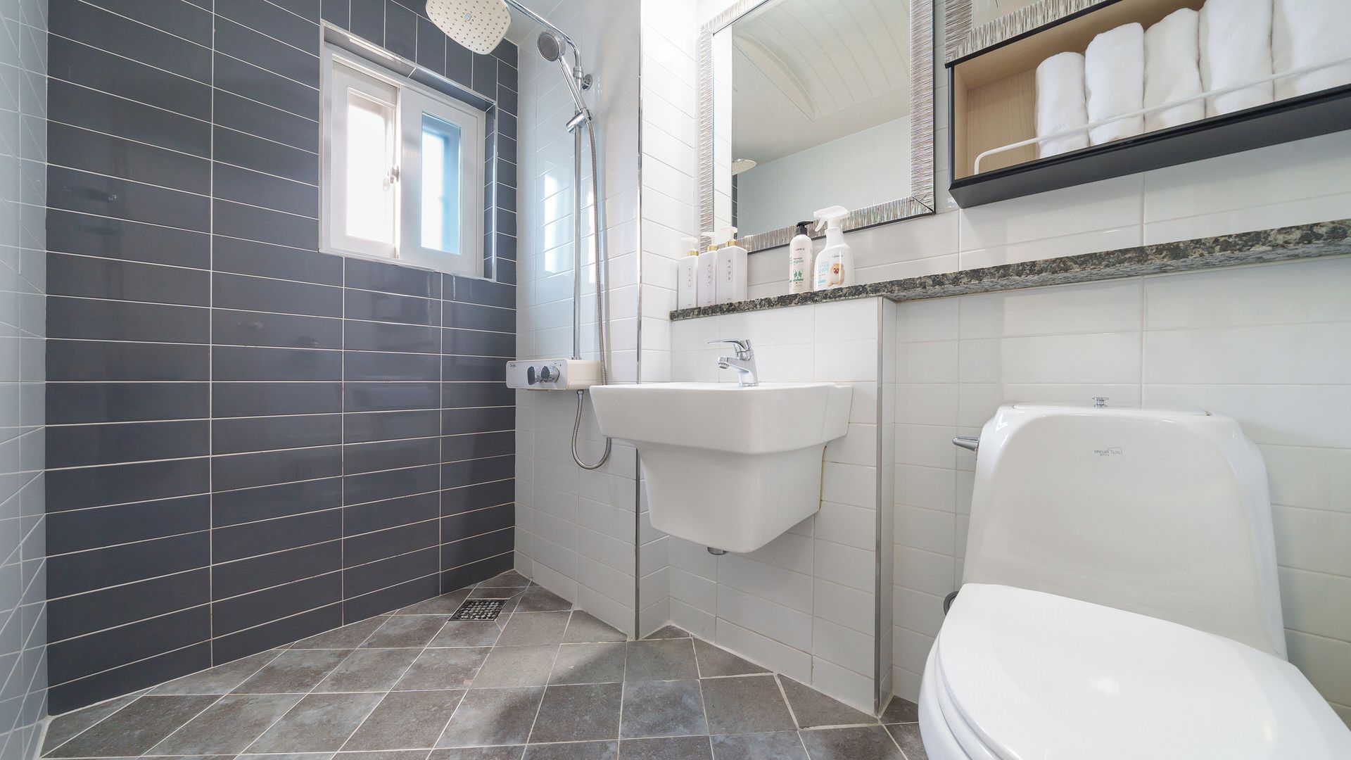 A bathroom with a shower, sink, toilet, and a mirror above the sink.