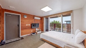 Une chambre d’hôtel moderne dotée d’un grand lit, d’une télévision, d’un mur en bois, d’un balcon avec vue et d’une porte coulissante.