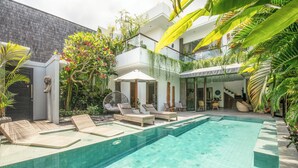 A modern pool area with lounge chairs, a small pool, and lush greenery. - Luxury 4BR Haven, Steps to Canggu's Beach Elegance (Canggu)