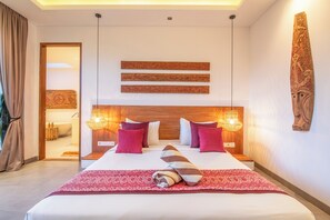 A hotel room with a large bed, two bedside lamps, a wooden headboard, and a view of the bathroom. - Luxury 4BR Haven, Steps to Canggu's Beach Elegance (Canggu)
