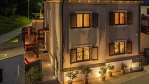 A two-story building with a satellite dish on the roof, multiple windows with shutters, and potted plants in front. - Villa with sea views and private jacuzzi (Krnica)