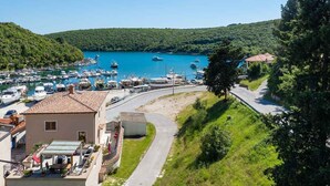 A coastal marina with boats docked, a road curving through the area, and a building with a tiled roof. - Villa with sea views and private jacuzzi (Krnica)