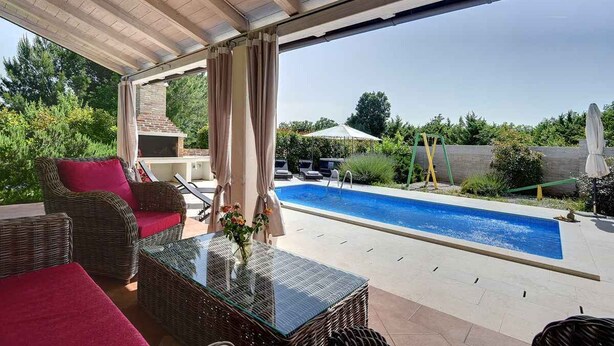 A covered outdoor area with wicker furniture, a glass table, and a swimming pool. - Villa mit Klimaanlage und Pool (Krnica)
