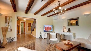 A spacious living room with a wooden ceiling, wicker furniture, a television, and a staircase leading to another room. - Villa mit Klimaanlage und Pool (Krnica)