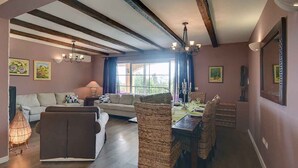 A dining area with a wooden table and wicker chairs, a sofa, and a chandelier. - Villa mit Klimaanlage und Pool (Krnica)