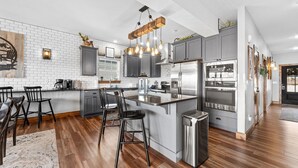 A modern kitchen with grey cabinets, stainless steel appliances, and a wooden island.