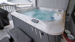 Un jacuzzi con panel de control, una silla y una ventana.