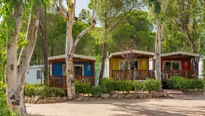 A row of small, colorful cabins with a dirt ground and trees in the background. - Mobilehome with parking (Tanca Manna)